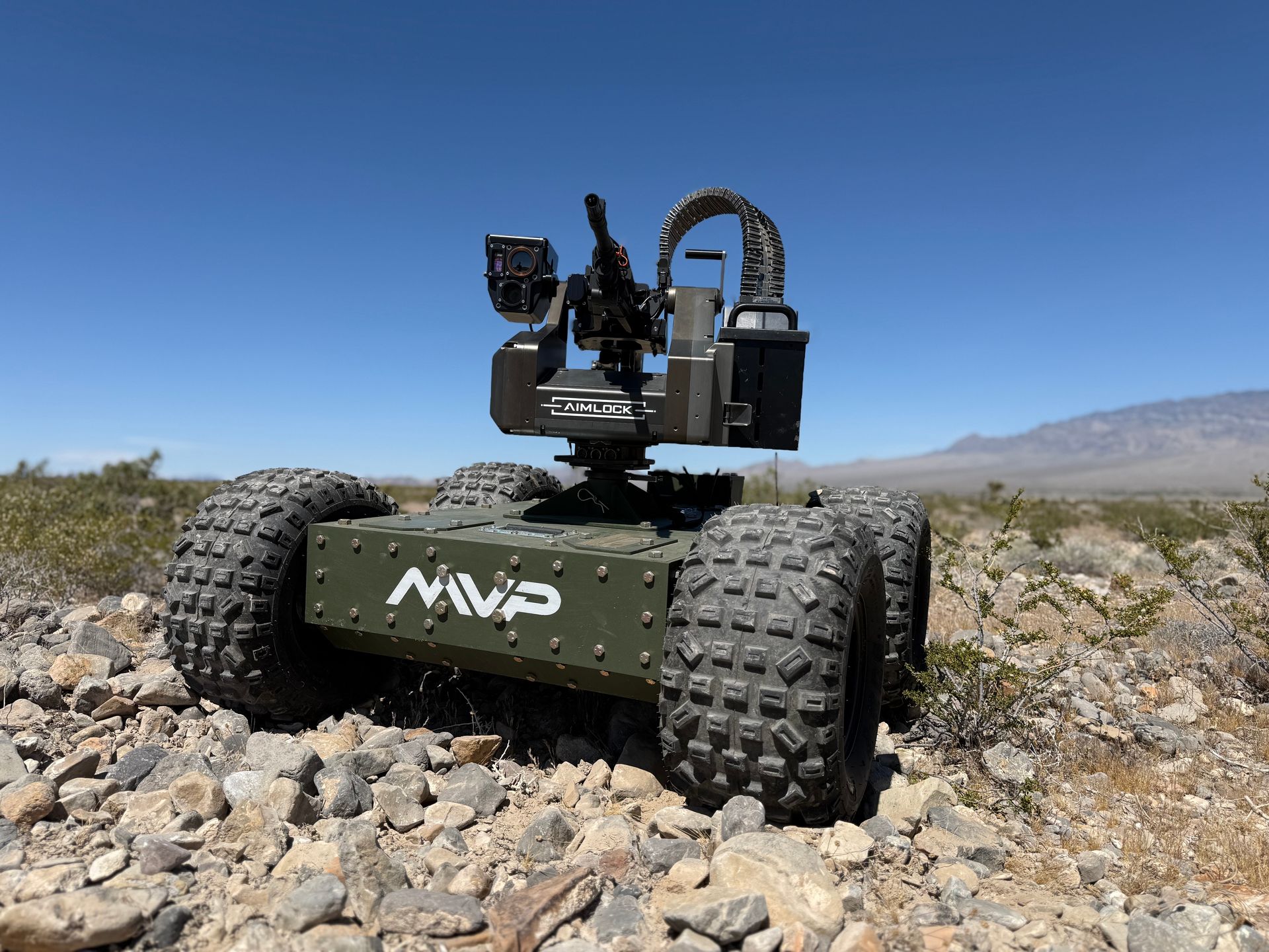 Rugged autonomous rover with large tires in a rocky desert landscape under a clear blue sky