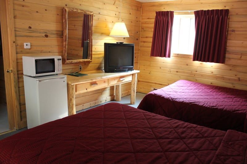 A hotel room with two beds , a microwave , and a flat screen tv.