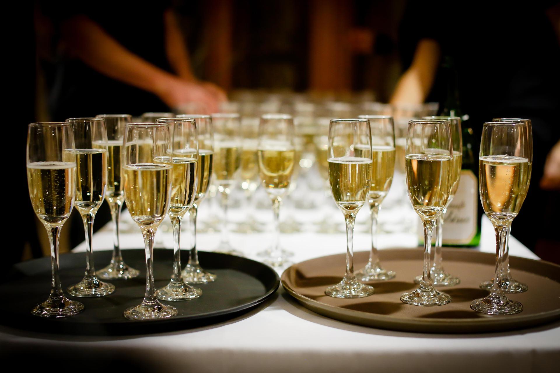 Zwei Tabletts mit Champagnergläsern stehen auf einem Tisch