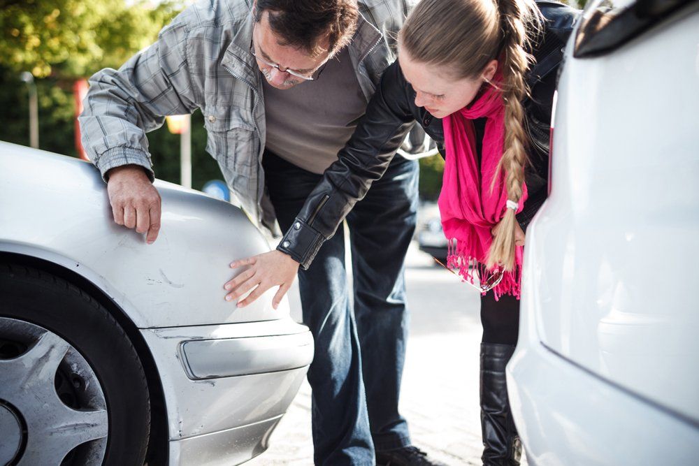 Man And Woman Examining Car After Accident — Port Washington, NY — Professional Insurance Consultants Inc.
