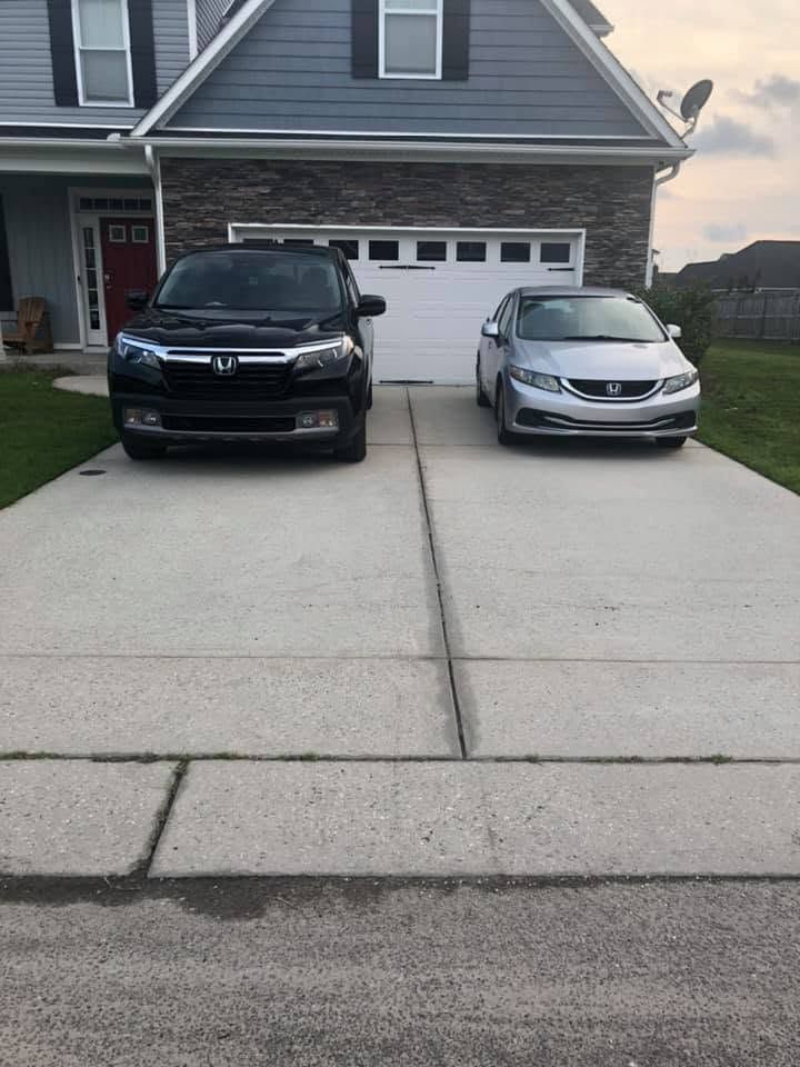Two cars parked in a suburban driveway in front of a gray house with a garage.