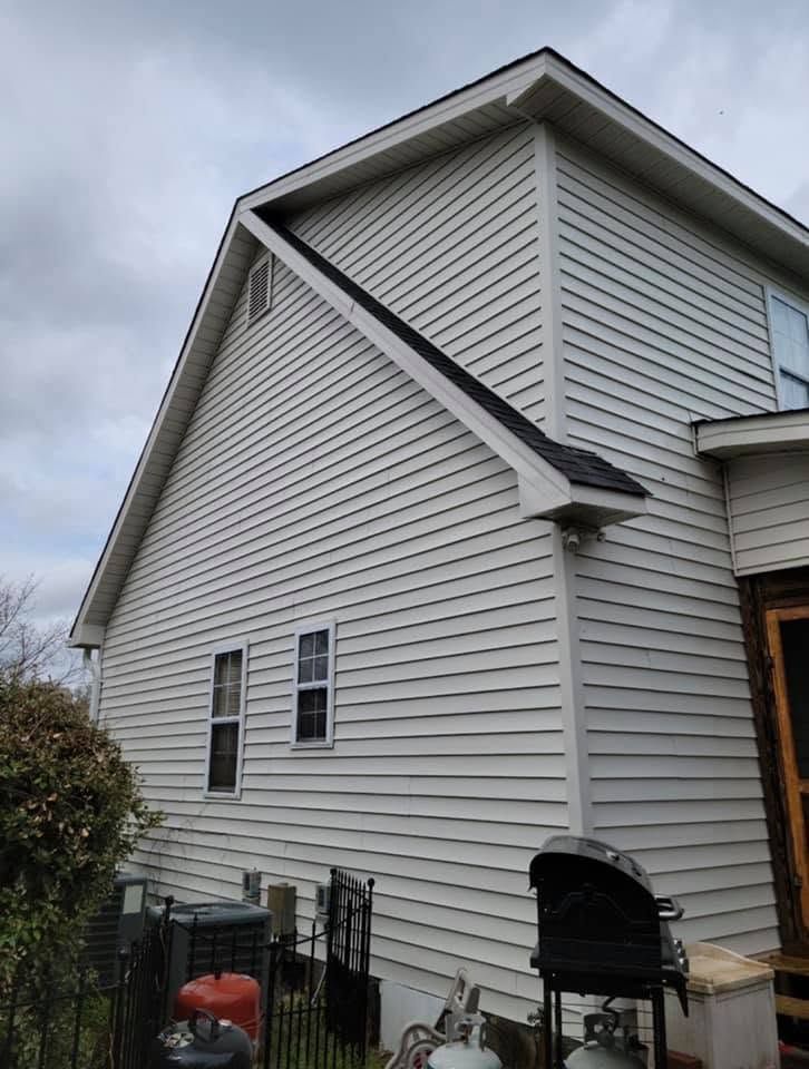 White house exterior with vinyl siding and a steep gable roof, viewed from the side.