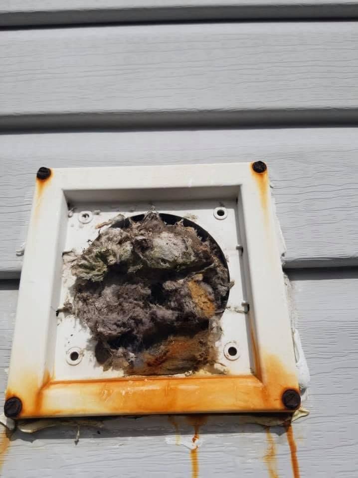 Melted, charred electrical outlet on gray siding with orange burn marks and debris inside