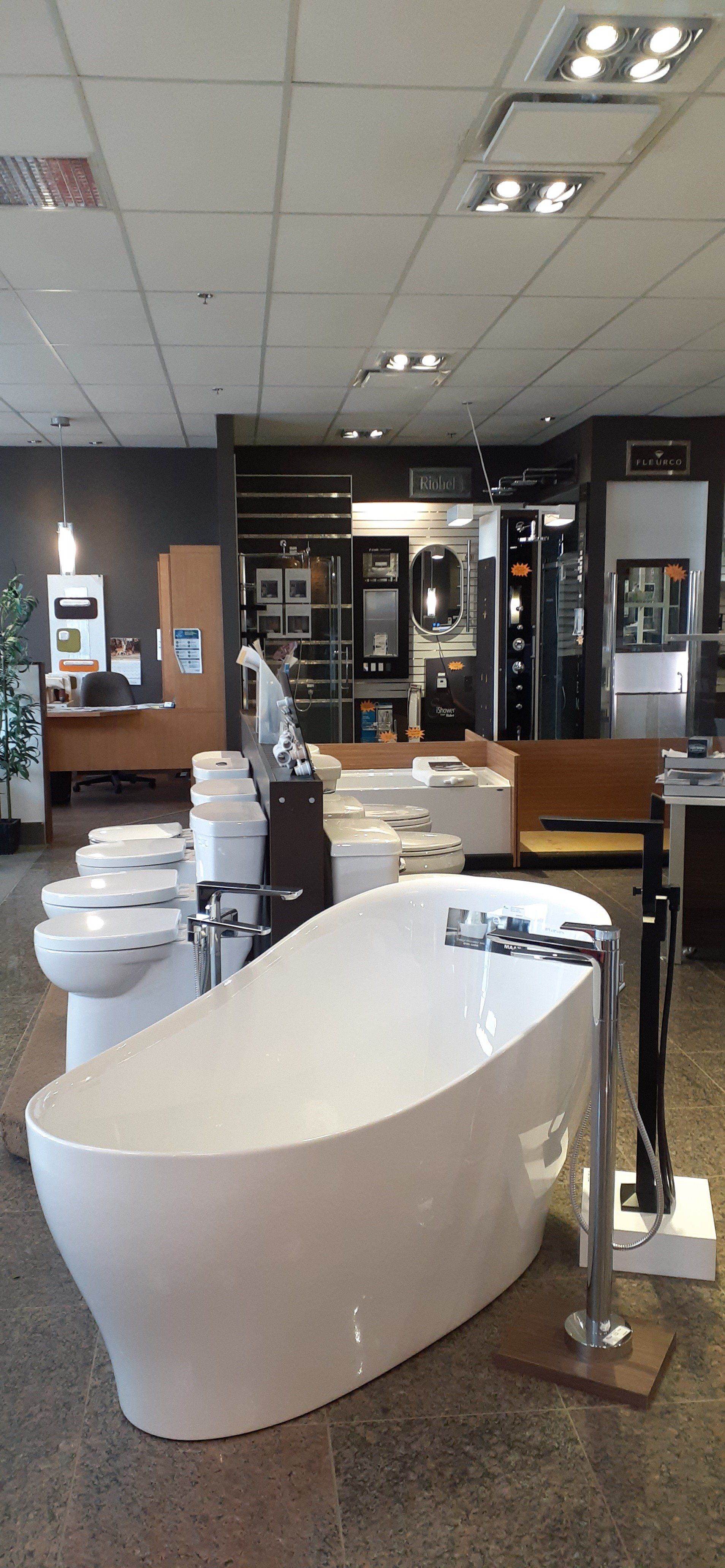 Une grande baignoire blanche se trouve au milieu d'une salle d'exposition de salle de bains.