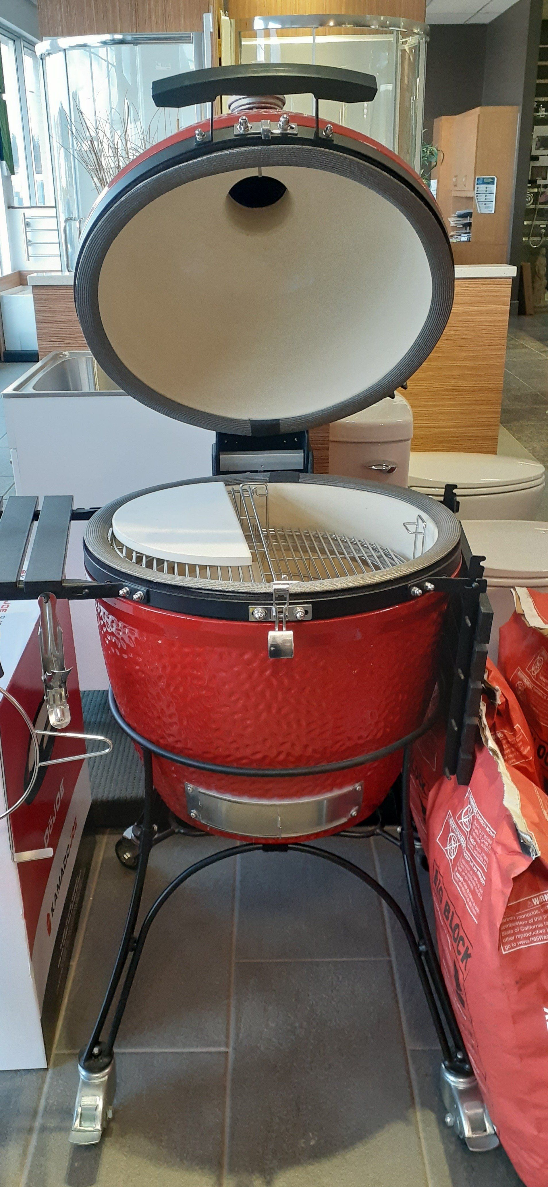 Un barbecue rouge est posé sur un sol carrelé dans un magasin.