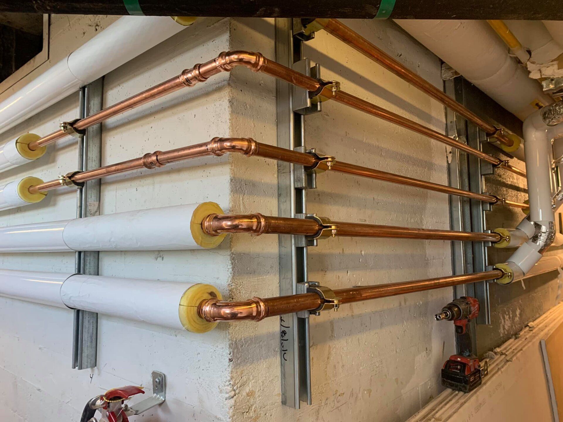 Une rangée de tuyaux en cuivre est alignée sur un mur.