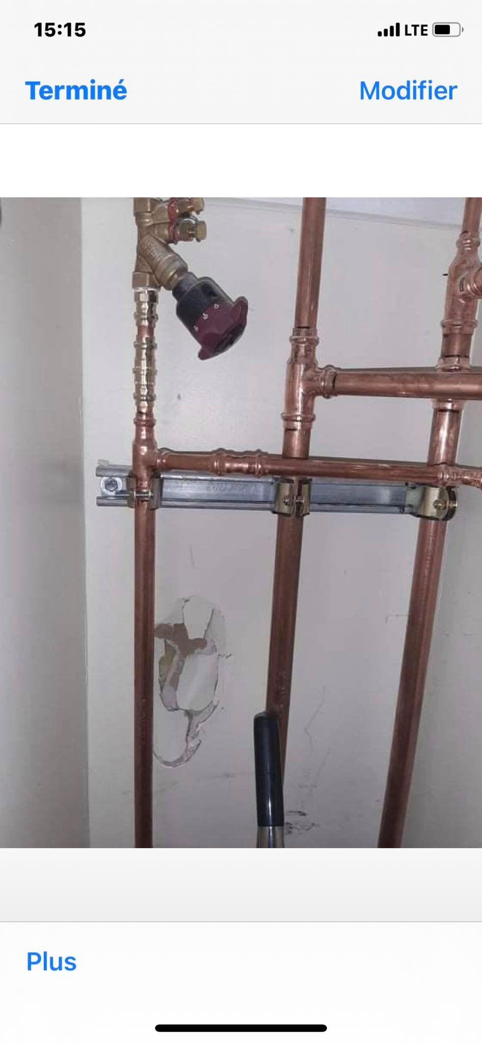 Un écran de téléphone montre une image de tuyaux en cuivre sur un mur.