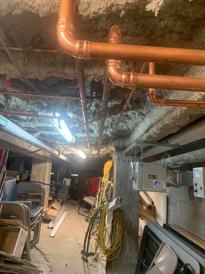 Une pièce avec beaucoup de tuyaux suspendus au plafond.