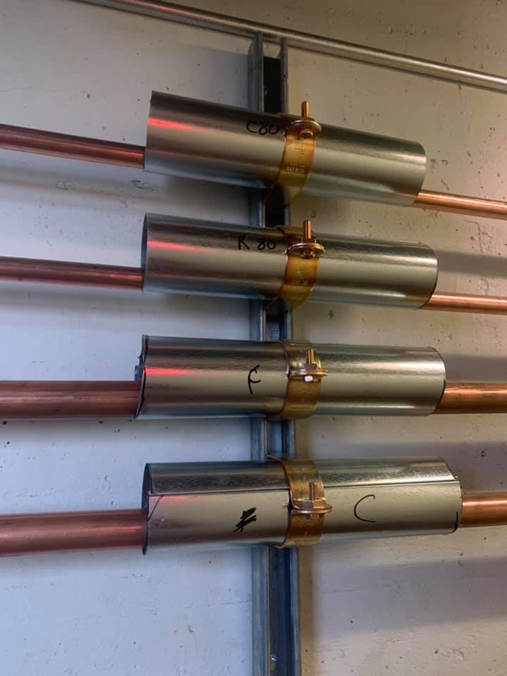 Une rangée de tuyaux métalliques et de tuyaux en cuivre sont alignés sur un mur.