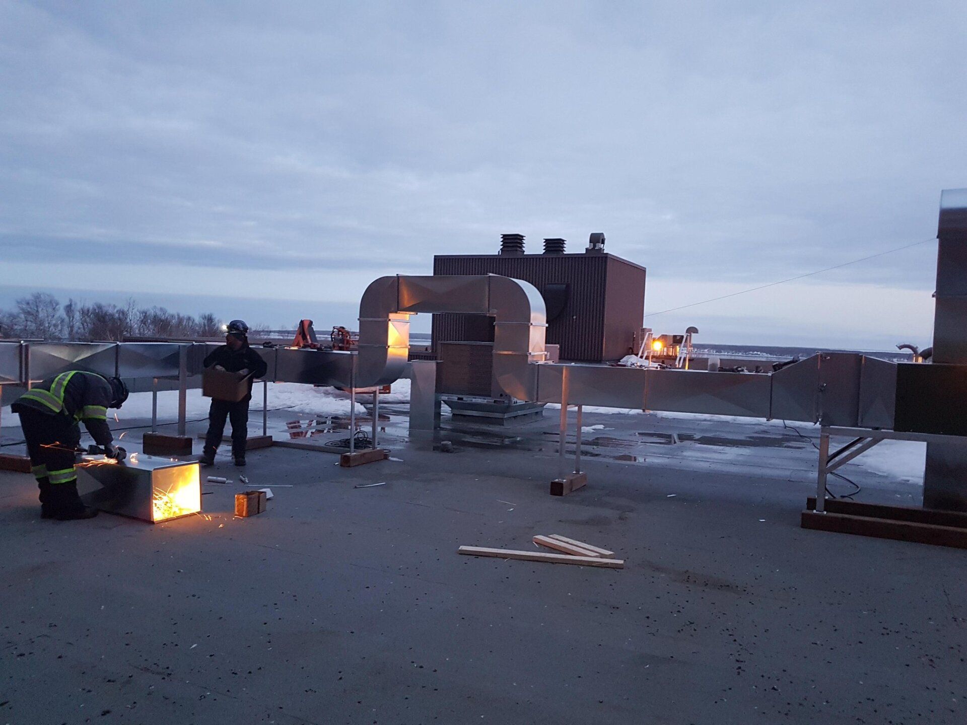 Deux hommes travaillent sur le toit d'un immeuble.