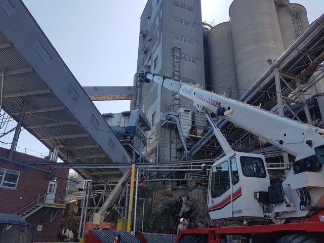 Une grue est assise sur un camion rouge devant un bâtiment.