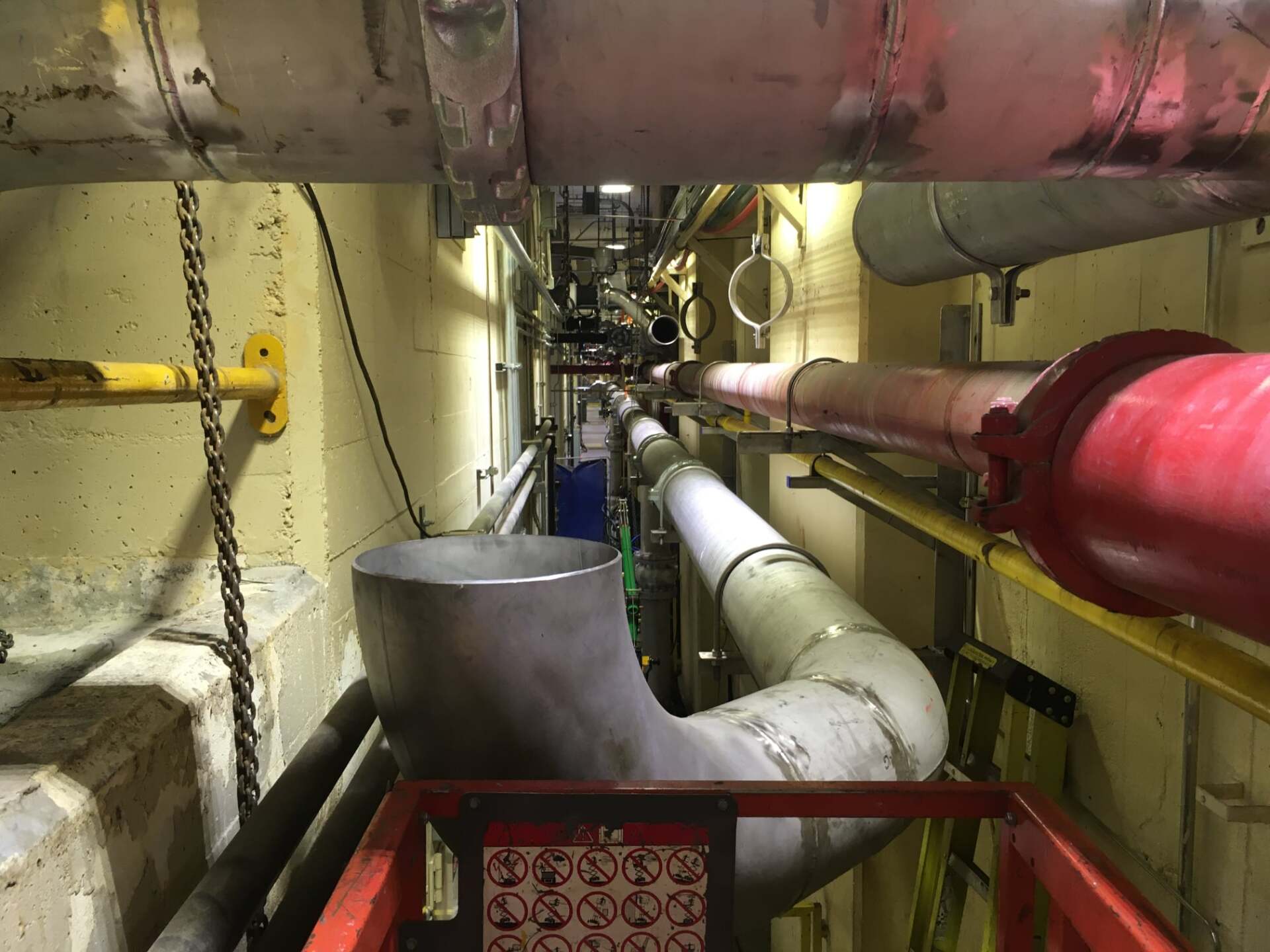 Un couloir étroit rempli de nombreux tuyaux et tubes.