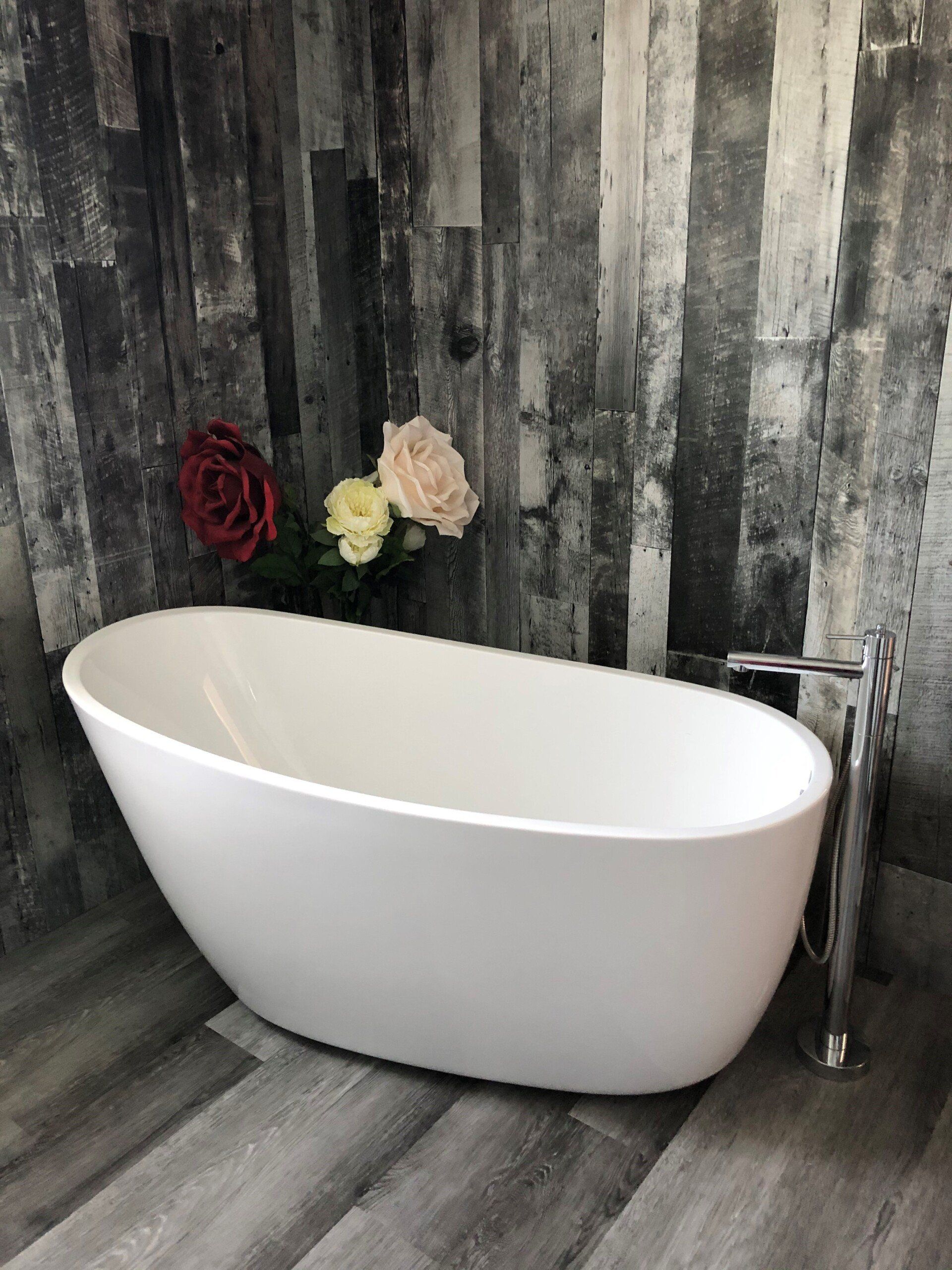Une baignoire blanche est posée sur un plancher en bois dans une salle de bain.
