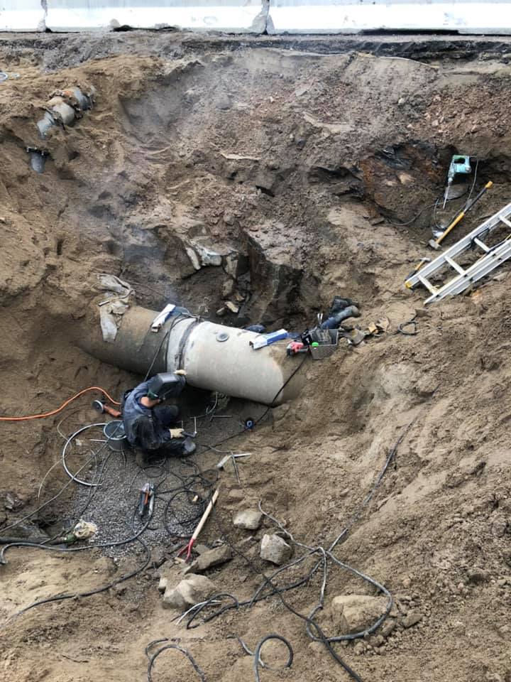Un homme soude un tuyau dans la terre.