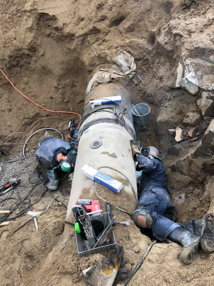Un homme soude un tuyau dans la terre.