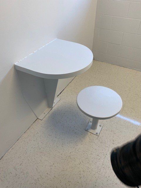 Une personne se tient dans une pièce avec deux tables blanches