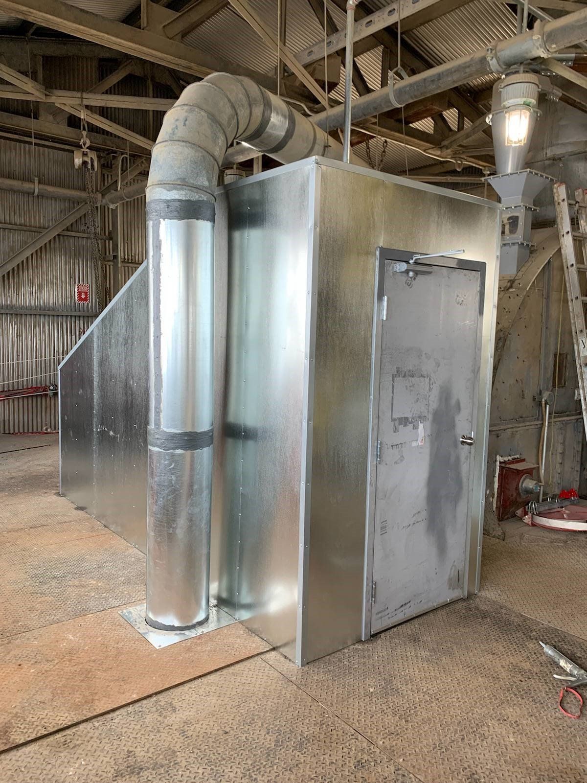 Un bâtiment en métal avec une porte et un tuyau qui en sort.
