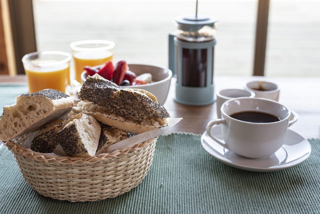 Desayuno con pan, fruta, café y zumo de naranja.