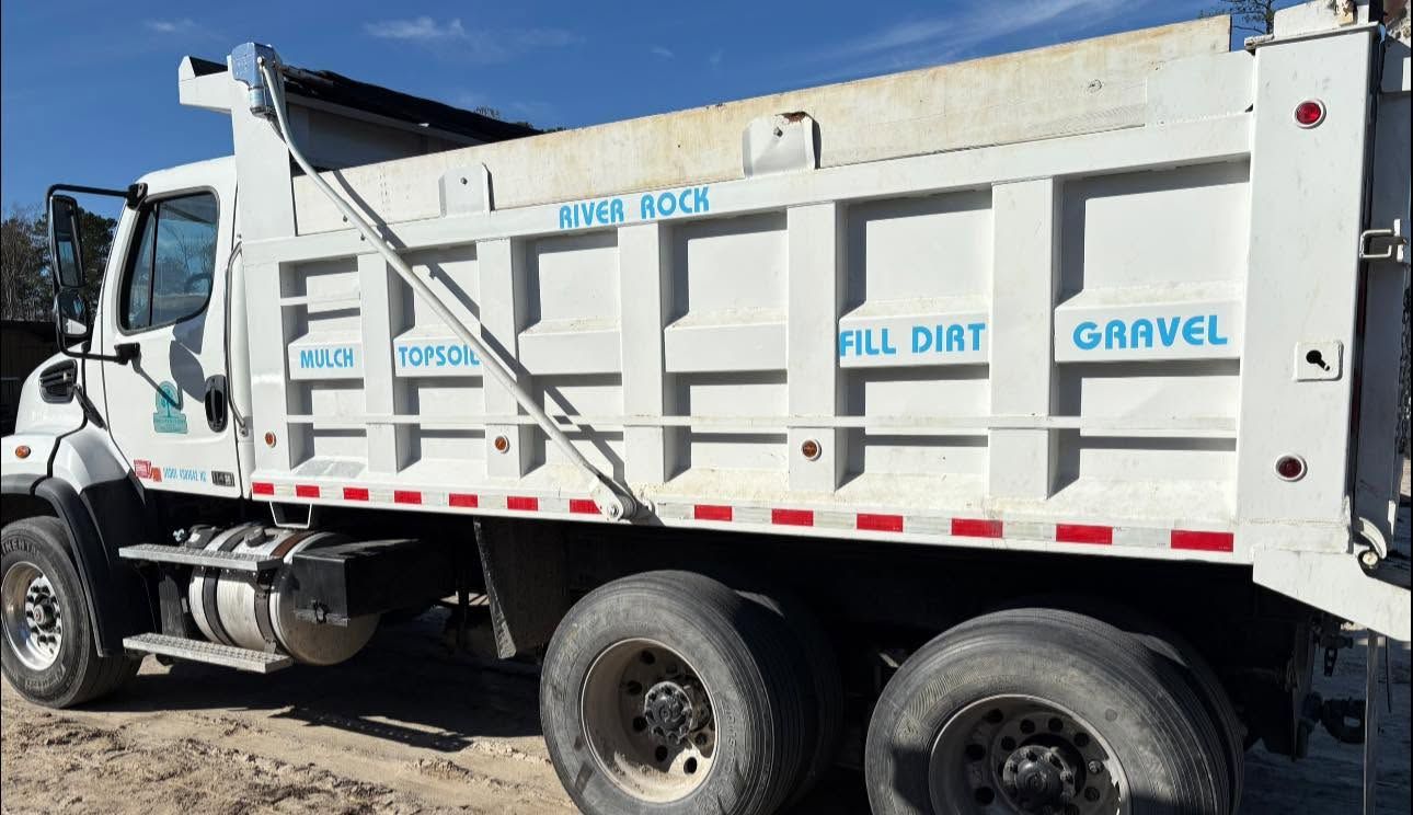White dump truck loaded with gravel, parked outdoors on a sunny day.