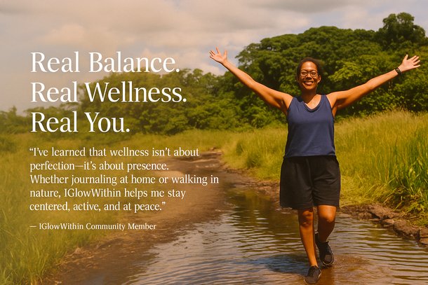Person smiling with arms raised in a shallow stream in a lush green landscape.