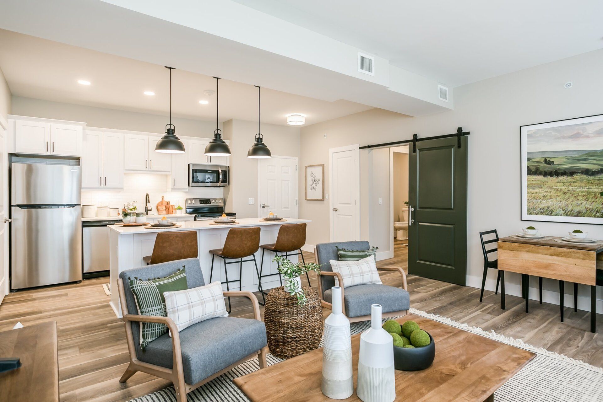 Bright living room and kitchen area with modern fixtures and barn doors