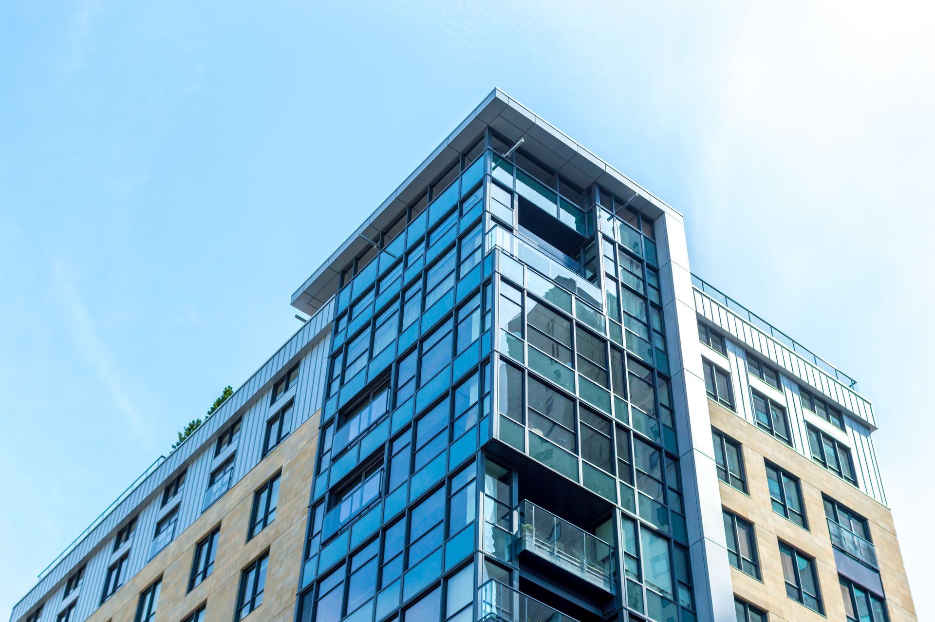 Immeuble moderne de grande hauteur avec des fenêtres en verre bleu et un ciel bleu clair.