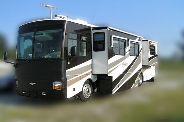 A large RV parked in an RV park with the slide out extended. 