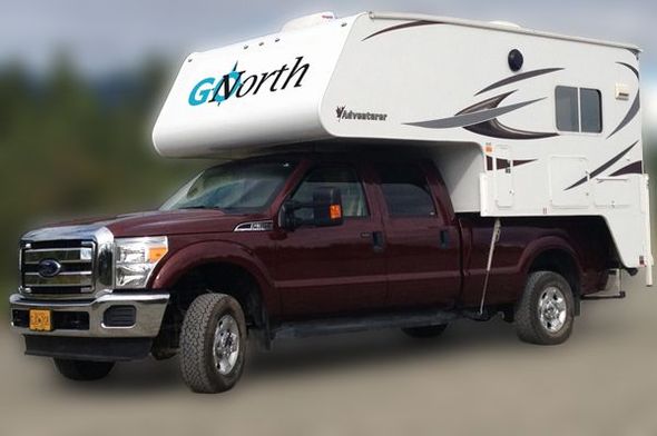 A camper sitting on a red ford truck needing repair by the side of the road. 