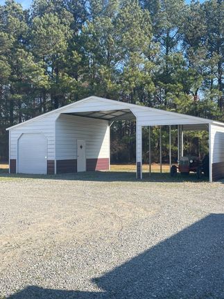 Tan storage shed with white trim, black hardware, and double doors outdoors.