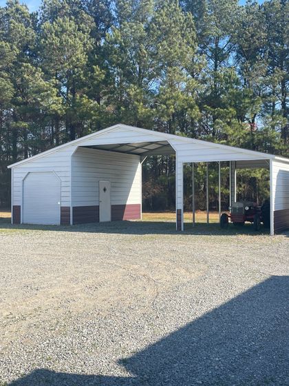 White and maroon metal carport with gravel driveway; trees in background.