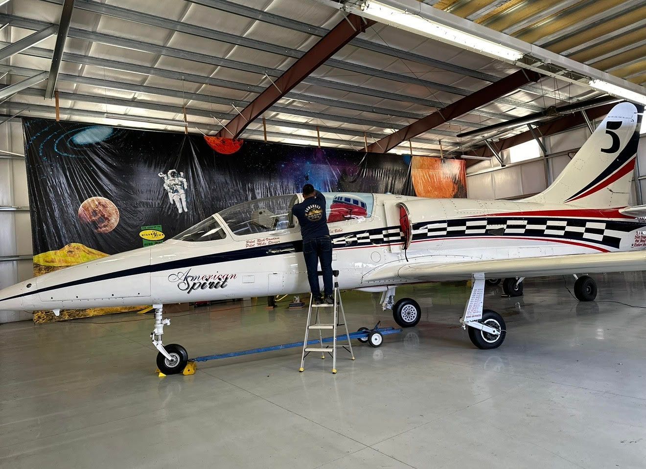 Black single-engine prop plane in a hangar, front view with spinning propeller and landing gear visible