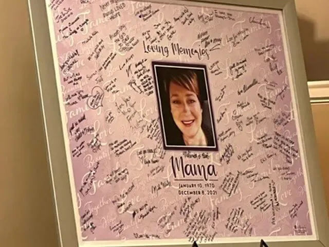 Framed pink memorial board covered with handwritten notes and a centered portrait photo.