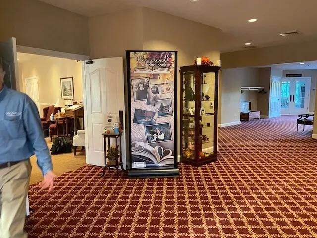 Hotel lobby with patterned carpet, display cases, and a person walking at the left edge