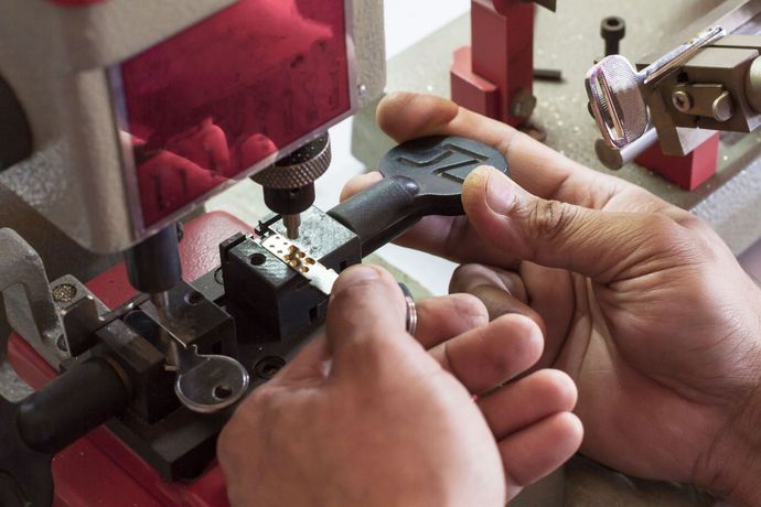 Hands using a machine to inspect a black plastic part in a workshop