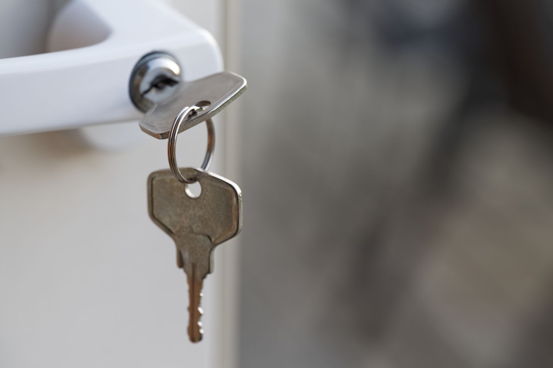 Hand using a screwdriver to remove a brass doorknob from a wooden door