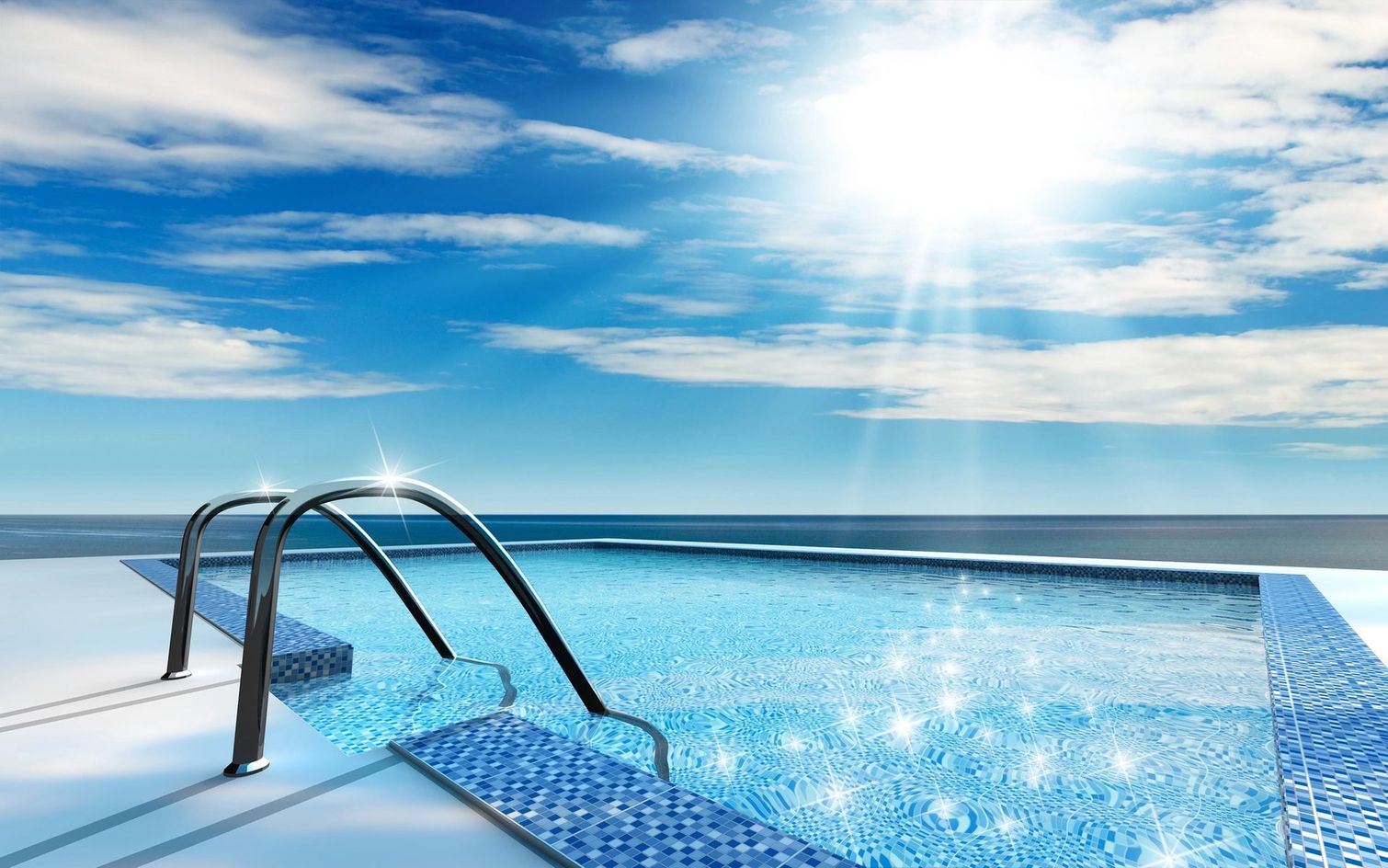 Piscina a sfioro con scaletta in metallo affacciata su un oceano blu intenso sotto un cielo soleggiato.