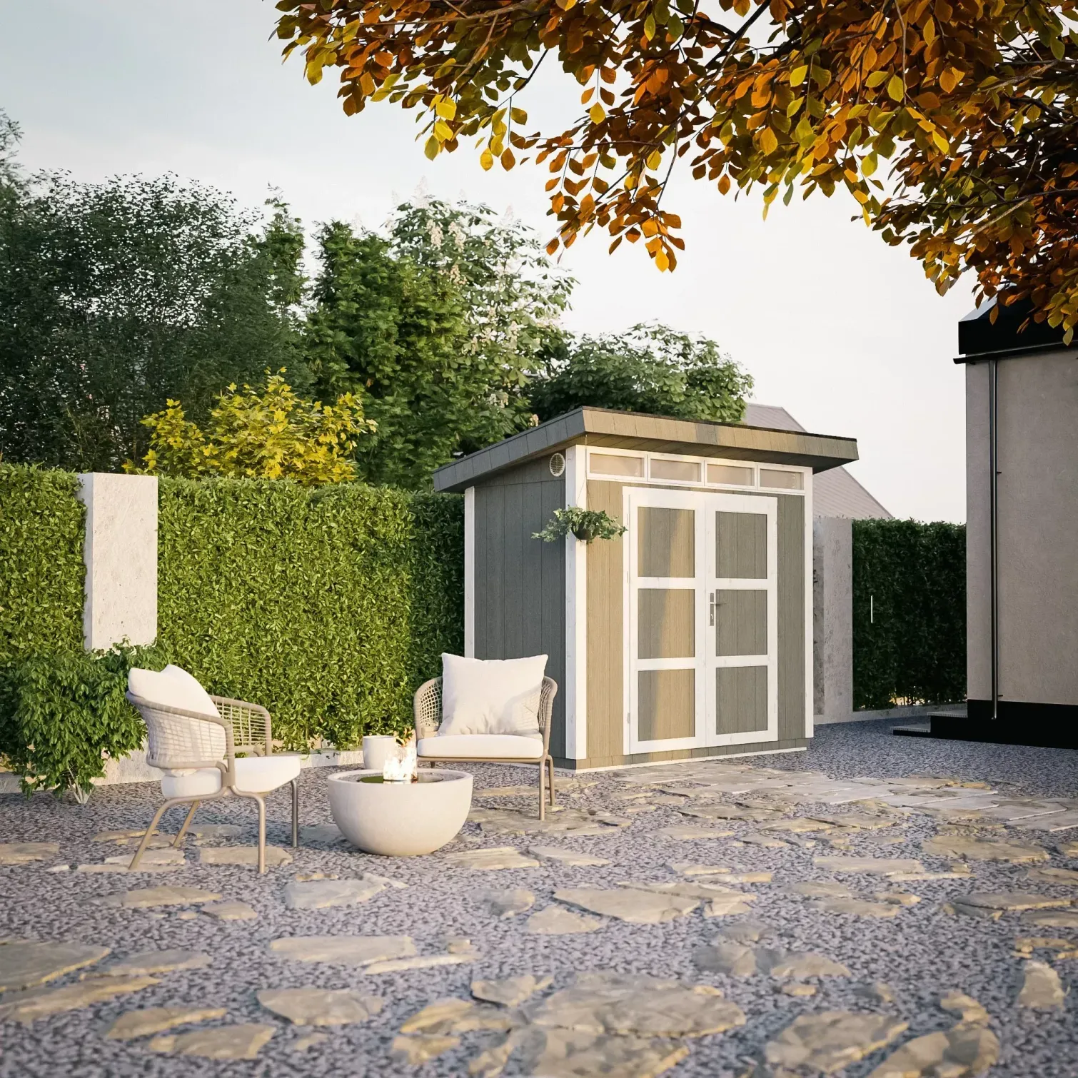 Patio soleggiato con sedie bianche, un tavolino, una siepe e una casetta da giardino grigia sotto alberi autunnali.