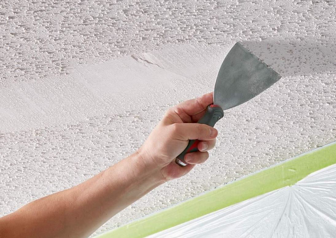 Hand scraping popcorn texture from a ceiling during a renovation project in Dallas, TX.