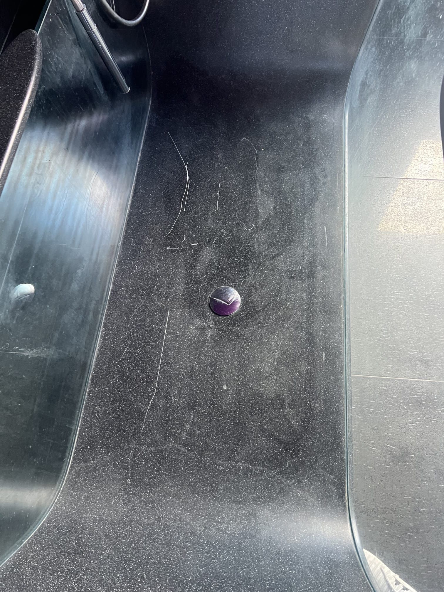 Intérieur du coffre noir avec une petite perle ou un petit bouton violet au centre du plancher.