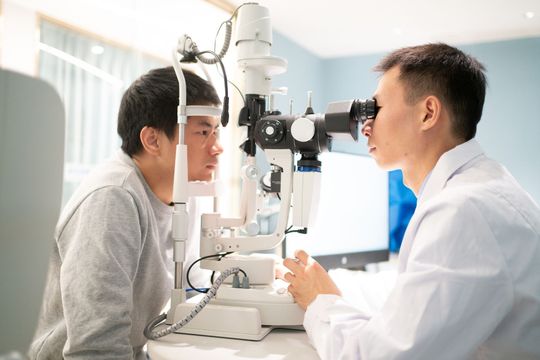 A male ophthalmologist using slit lamp to inspect patient's vision