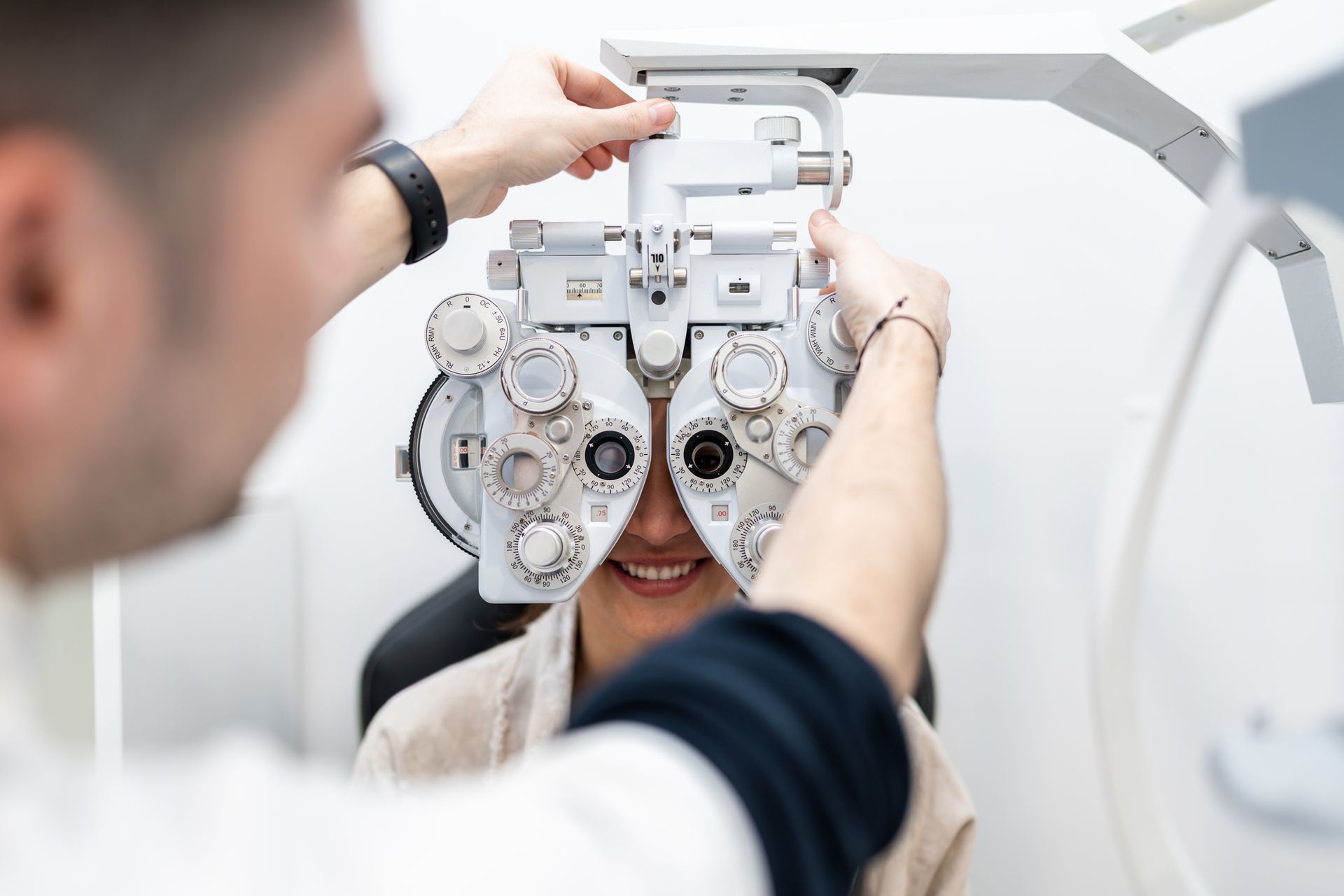 Ophthalmologist adjusting phoropter during eye examination for young woman. Ophthalmologist adjusting phoropter during eye examination for young woman.