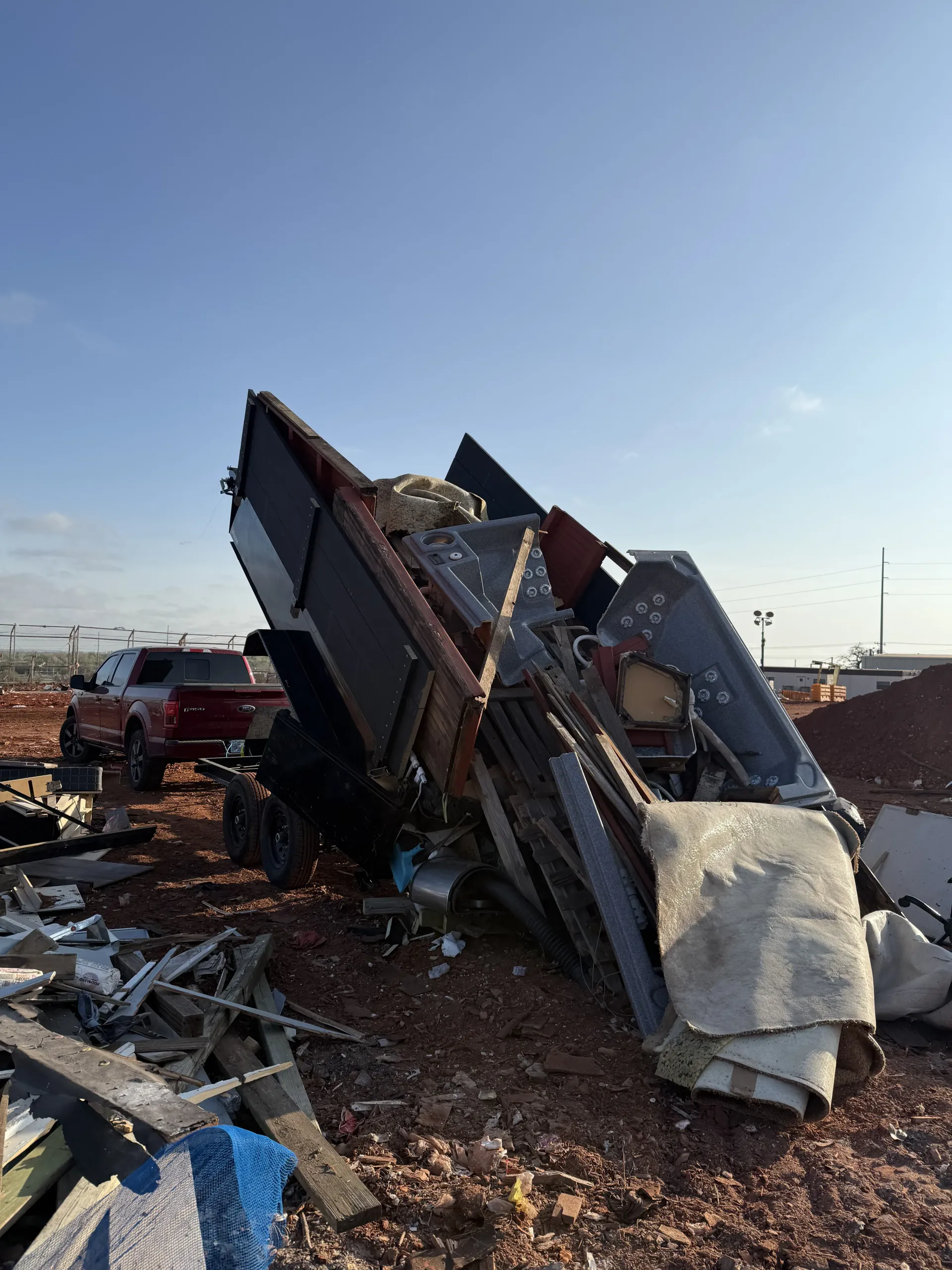 Collapsed wrecked vehicle on a debris-strewn roadside under a clear blue sky