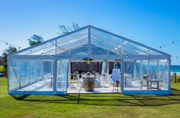 A clear tent is sitting on top of a lush green field.