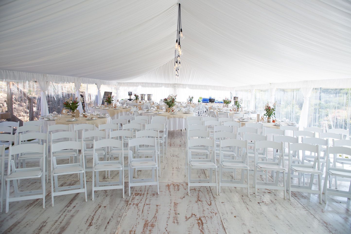 A large white tent filled with white chairs and tables
