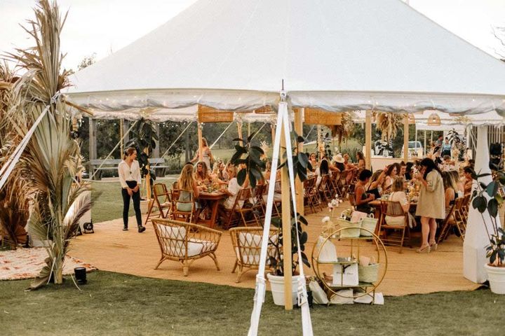 A group of people are sitting at tables under a tent.