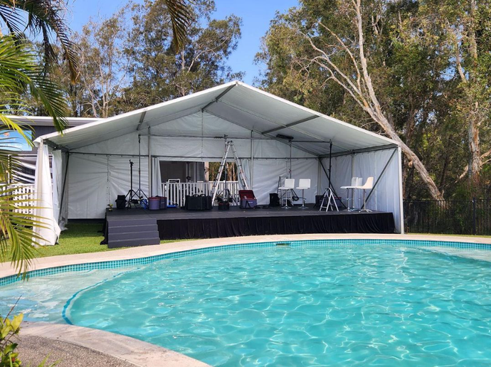 A large white tent is sitting next to a swimming pool.