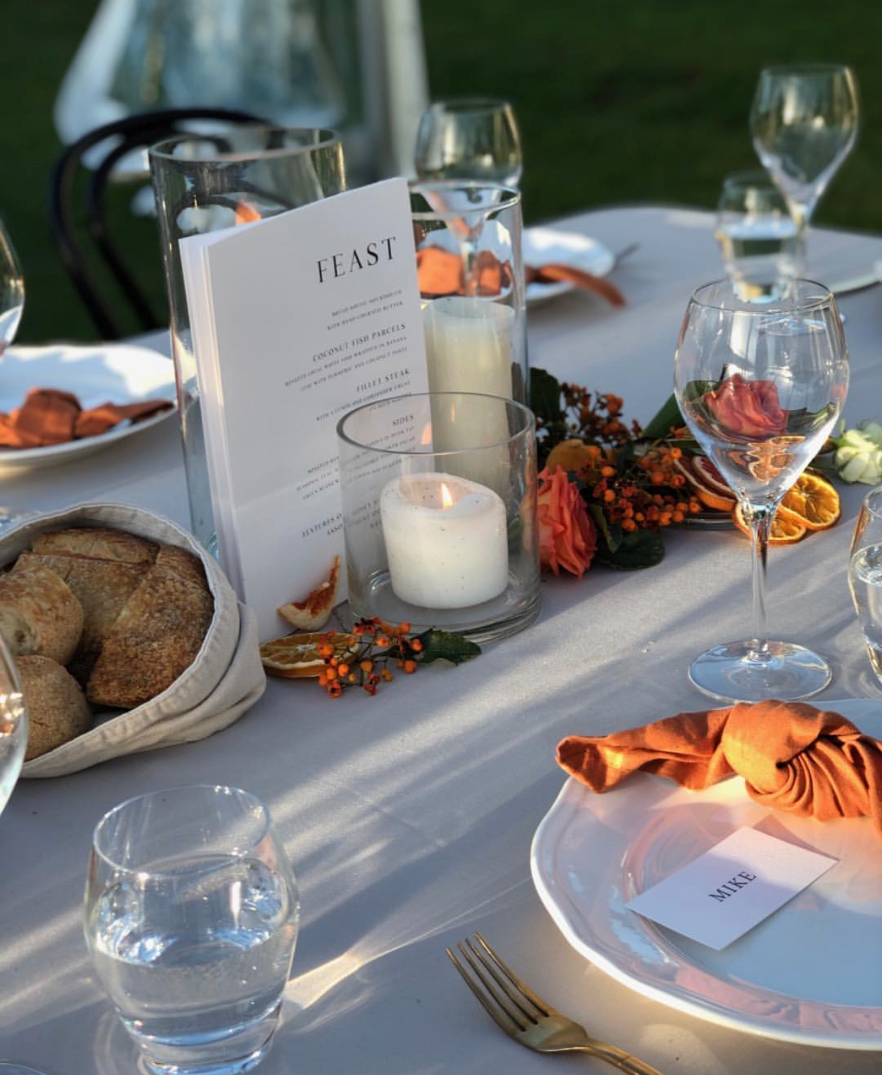 A table set for a feast with plates , glasses , candles and a menu.