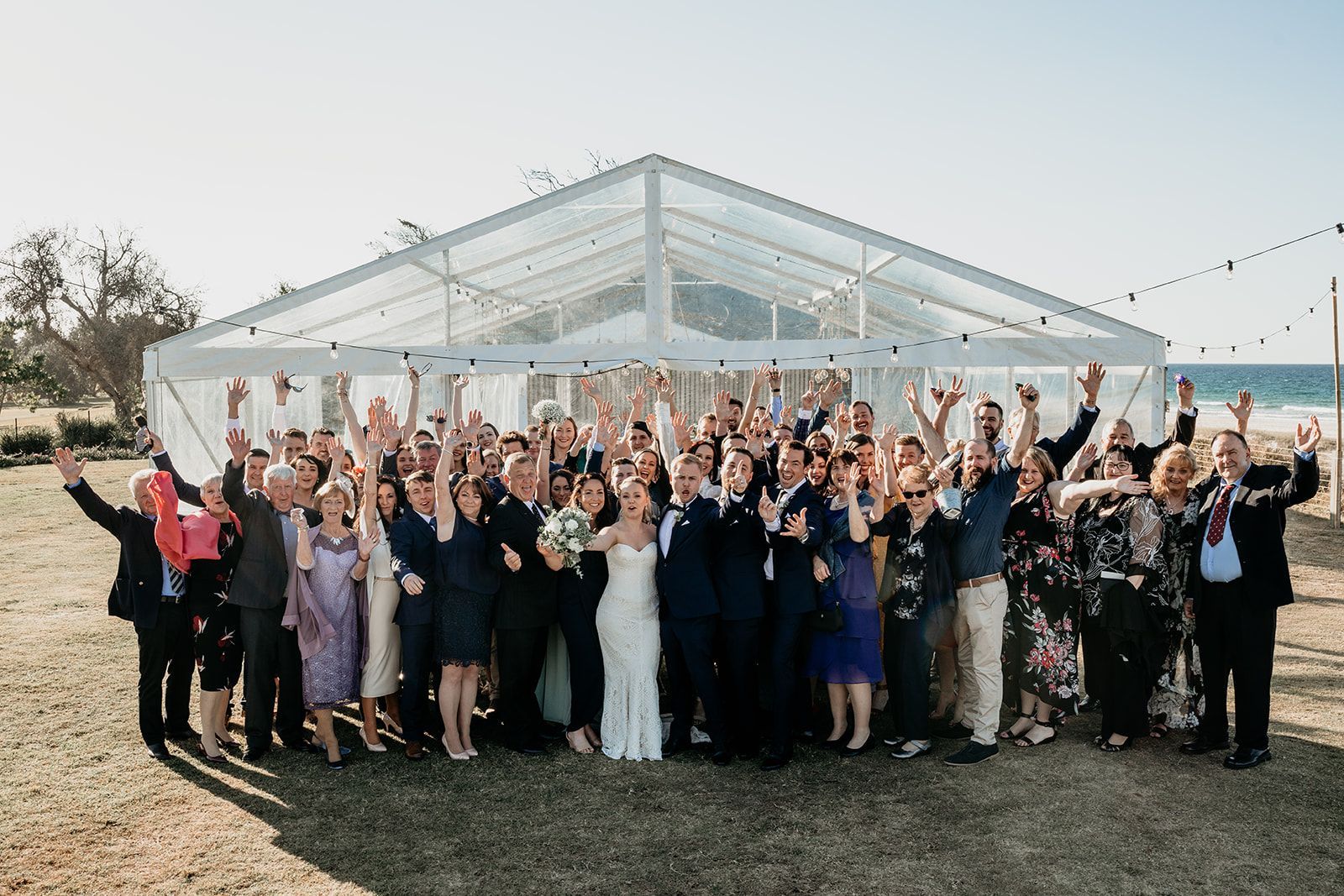 A large group of people are posing for a picture in front of a clear tent.