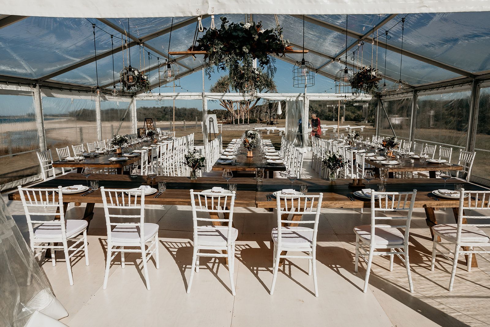 A long table and chairs under a clear tent.
