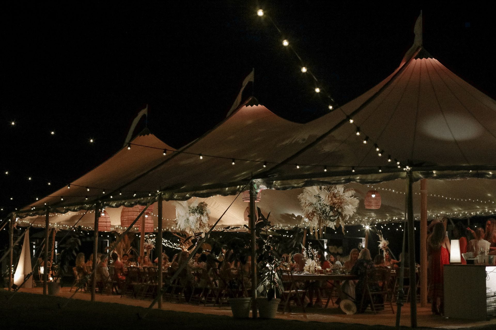 A group of people are sitting under a tent at night